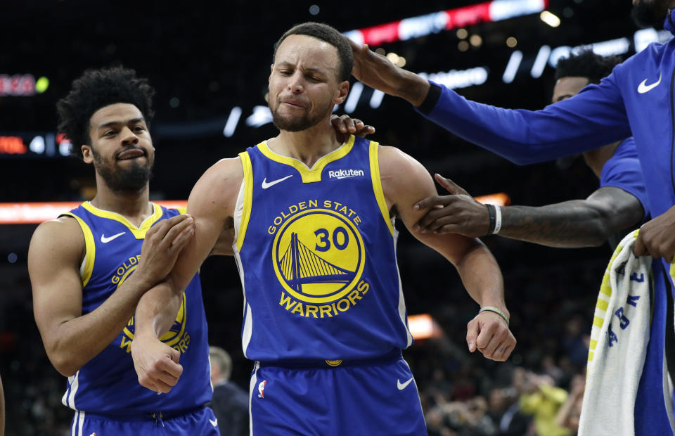 Golden State Warriors guard Stephen Curry (30) is grabbed by teammates as he reacts after being called for a foul during the second half of an NBA basketball game against the San Antonio Spurs in San Antonio, Monday, March 18, 2019. (AP Photo/Eric Gay)