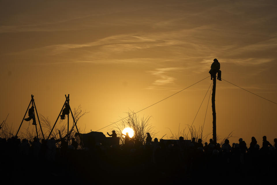 Climate activists sit in so-called tripods and on a tree trunk at the village of Luetzerath near Erkelenz, Germany, Tuesday, Jan. 10, 2023. The village of Luetzerath has to be demolished to expand the Garzweiler lignite coal mine near the dutch border. (AP Photo/Michael Probst)