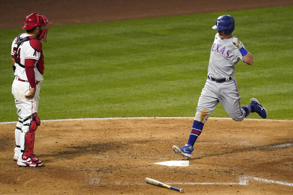 Texas Rangers' Nick Solak, right, scores on a sacrifice fly hit by Jose Trevino as Los Angeles Angels catcher Kurt Suzuki stands at the plate during the sixth inning of a baseball game Monday, April 19, 2021, in Anaheim, Calif. (AP Photo/Mark J. Terrill)