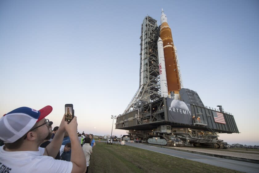 Invitados y empleados de la NASA toman fotografías en el momento en que el Cohete del Sistema de Lanzamiento Espacial de la NASA, con la nave Orion a bordo, es llevado al edificio de Ensamblaje Vehicular por primera vez, el jueves 17 de marzo de 2022, en el Centro Espacial Kennedy, en Cabo Cañaveral, Florida. (Aubrey Gemignani/NASA vía AP, archivo)