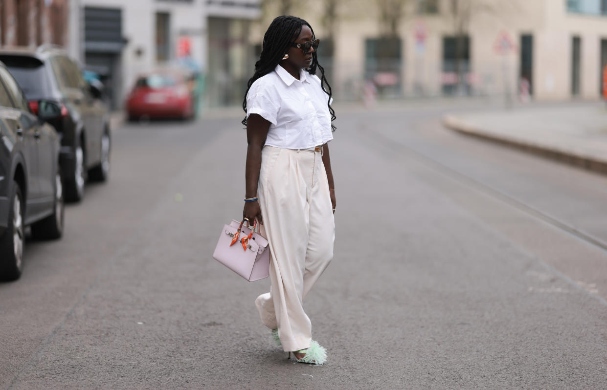 ASML Asos - Lois Opoku seen wearing Julian Daynov x Rossi beige suit pants, Hermes Kelly white leather yellow gold belt, Zara white blouse, Hermes beige and rosé Birkin 25 bag with orange details, ASOS golden statement earrings and Zara feather light green heels on April 01, 2024 in Berlin, Germany. (Photo by Jeremy Moeller/Getty Images)