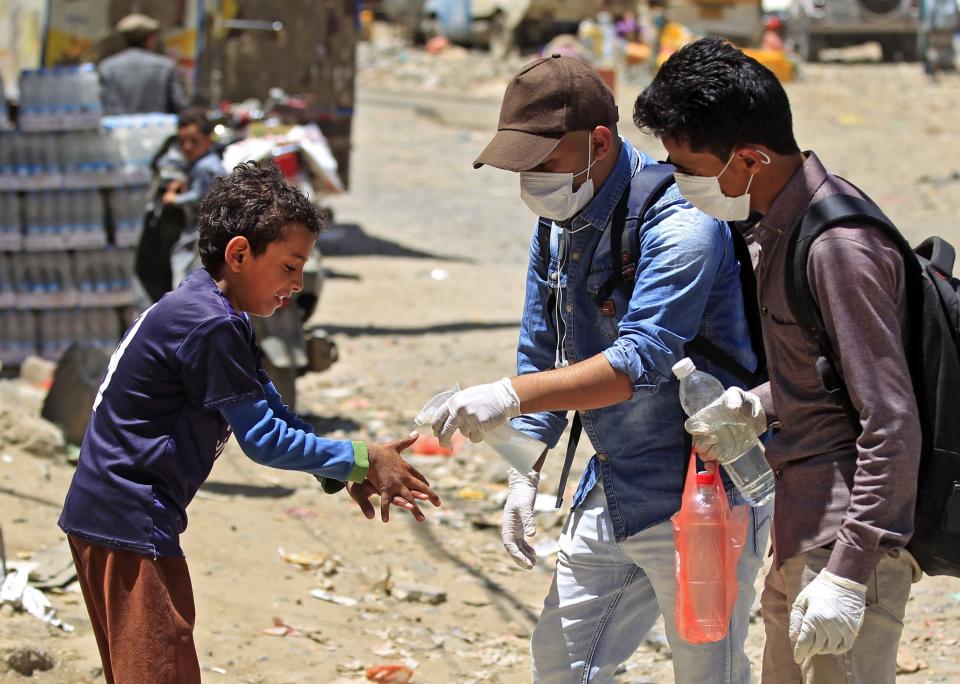 A volunteer in Sanaa, Yemen, sprays disinfectant on the hands of a boy in the one of the city's poor neighborhoods on March 30. (Photo: MOHAMMED HUWAIS/AFP via Getty Images)