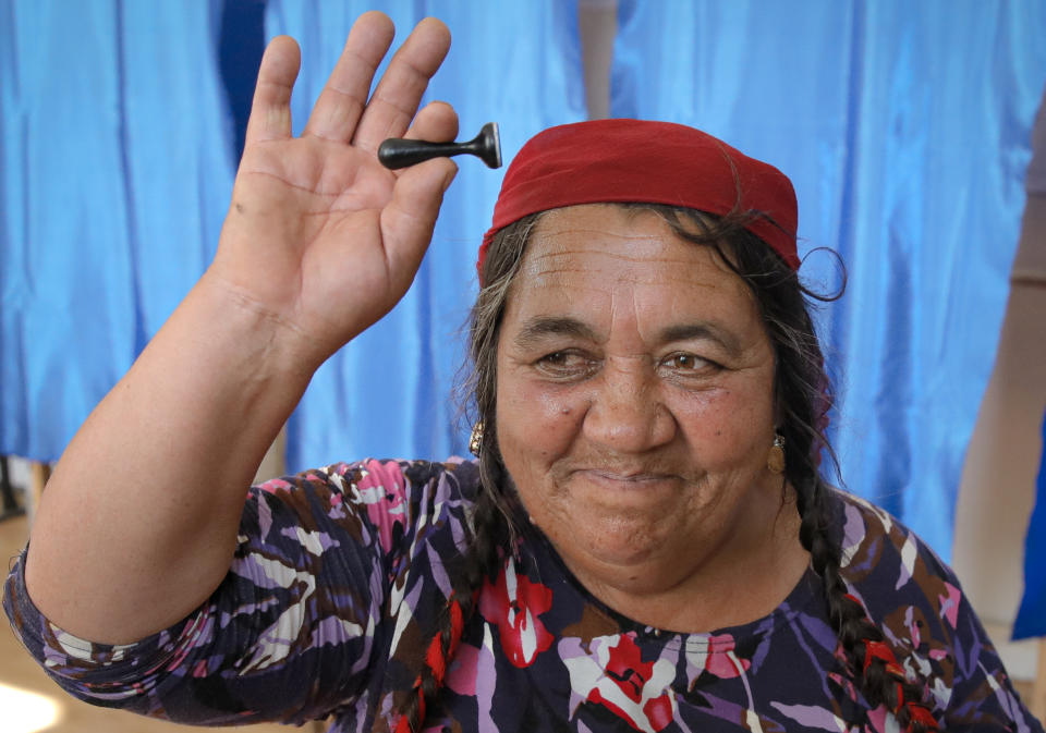 A woman holds up the voting stamp she used, at a polling station in Sintesti, Romania, Sunday, Nov. 10, 2019. Romania held a presidential election Sunday after a lackluster campaign that has been overshadowed by the country's political crisis, which saw a minority government installed just a few days ago. (AP Photo/Vadim Ghirda)