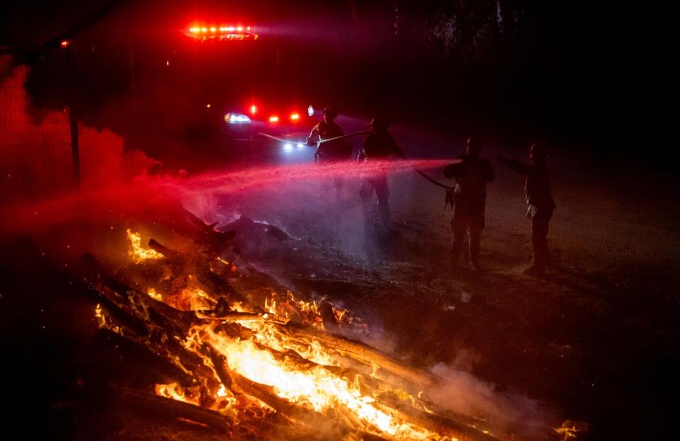 Firefighters douse flames while battling the Highland Fire in Aguanga on Monday (AP)