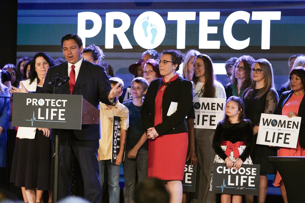 Florida Gov. Ron DeSantis, left, speaks to supporters before signing a 15-week abortion ban into law Thursday, April 14, 2022, in Kissimmee, Fla.  The move comes amid a growing conservative push to restrict abortion ahead of a U.S. Supreme Court decision that could limit access to the procedure nationwide.  (AP Photo/John Raoux)