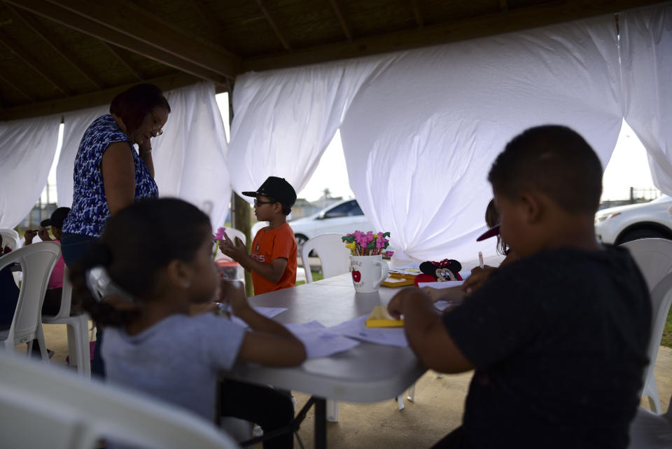 Alumnos de kindergarten asisten a clases en una glorieta de un parque deportivo municipal de Santa Isabel, Puerto Rico, el 4 de febrero del 2020. Las cortinas ayudan a protegerlos del sol. (AP Photo/Carlos Giusti)