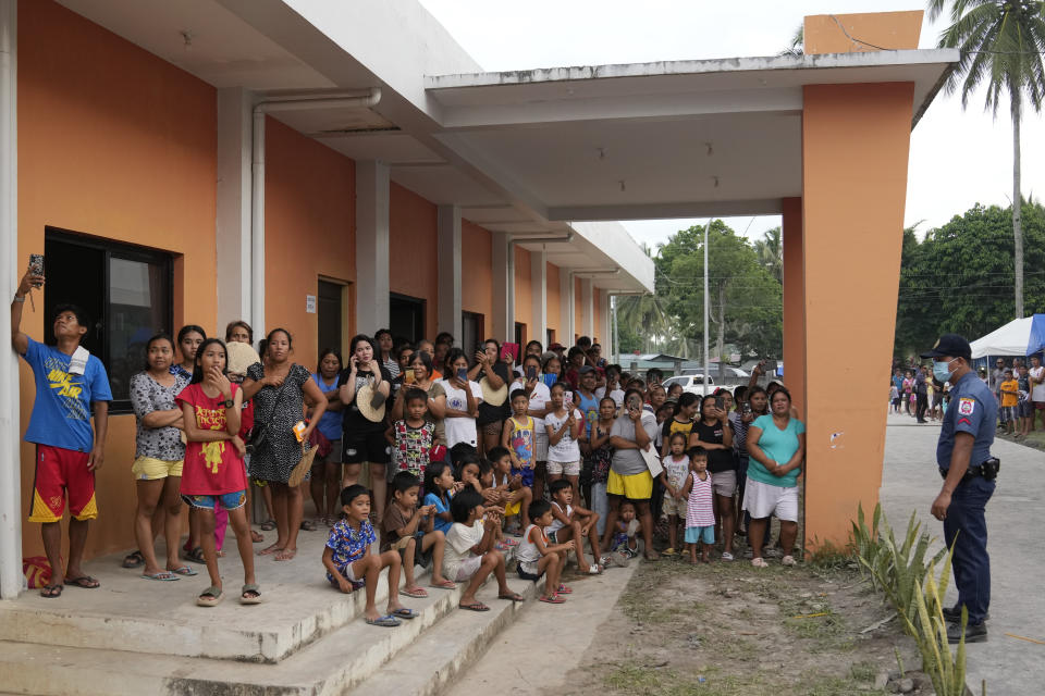 Evacuees watch from a building to catch a glimpse of Philippine President Ferdinand Marcos Jr. as he visited an evacuation center in Guinobatan town, Albay province, northeastern Philippines, Wednesday, June 14, 2023. A gentle eruption of the Philippines' most active volcano that has forced nearly 18,000 people to flee to emergency shelters could last for months and create a protracted crisis, officials said Wednesday. (AP Photo/Aaron Favila)