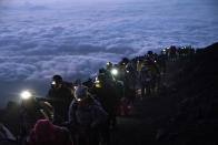 A group of hikers climb to the top of Mount Fuji just before sunrise as clouds hang below the summit Tuesday, Aug. 27, 2019, in Japan. (AP Photo/Jae C. Hong)