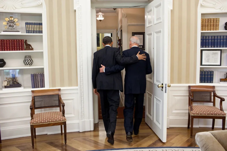 Barack Obama embraces Joe Biden as they walk out of the Oval Office