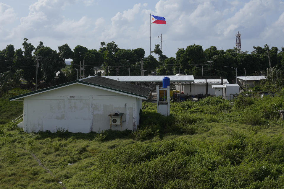 A Philippine flag is seen beside houses and structures at the Philippine-occupied Thitu island, locally called Pag-asa island, on Friday, Dec. 1, 2023 at the disputed South China Sea. The Philippine coast guard inaugurated a new monitoring base Friday on a remote island occupied by Filipino forces in the disputed South China Sea as Manila ramps up efforts to counter China's increasingly aggressive actions in the strategic waterway. (AP Photo/Aaron Favila)