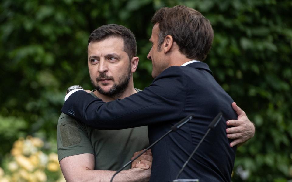 Ukrainian President Volodymyr Zelensky and French President Emmanuel Macron shake hands and hug after a press conference - Getty Images