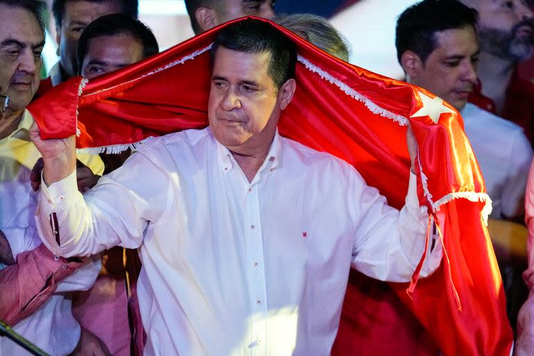 ARCHIVO - El expresidente Horacio Cartes se cubre con una bandera del gobernante Partido Colorado después del cierre de las urnas durante las elecciones generales en Asunción, Paraguay, el 30 de abril de 2023.