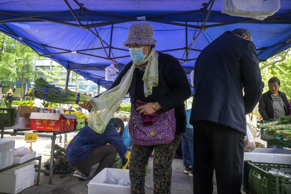 People wearing face masks shop for fresh vegetables at a pop-up market in Beijing, Thursday, April 28, 2022. Beijing shifted more classes online Thursday in a further tightening of COVID-19 restrictions, as China's capital seeks to prevent a wider outbreak. (AP Photo/Mark Schiefelbein)