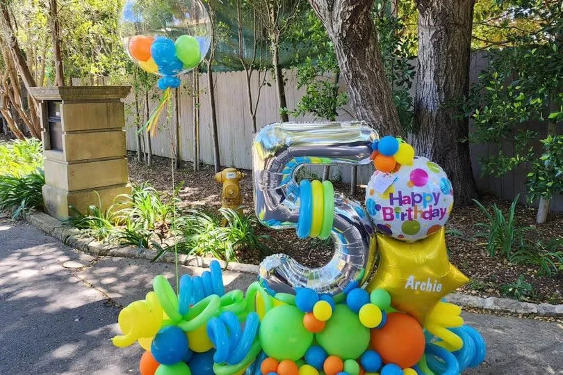 The picture shows a huge silver inflatable number five surrounded by an array of different-shaped multicoloured balloons.