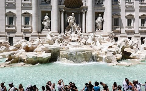 Tourists gather by the Trevi Fountain during an unusually early summer heatwave  - Credit: AFP