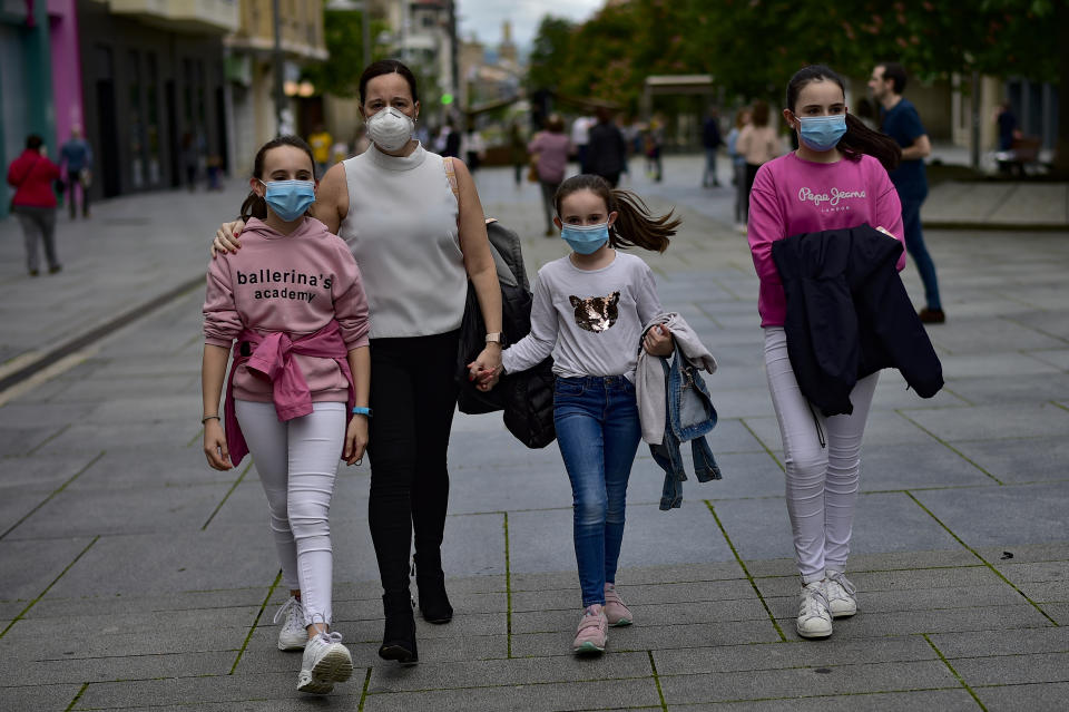 A family wearing face mask to protect of the coronavirus go for a walk at Carlos III promenade, in Pamplona, northern Spain, Sunday, April 27, 2020. On Sunday, children under 14 years old will be allowed to take walks with a parent for up to one hour and within one kilometer from home, ending six weeks of compete seclusion. (AP Photo/Alvaro Barrientos)