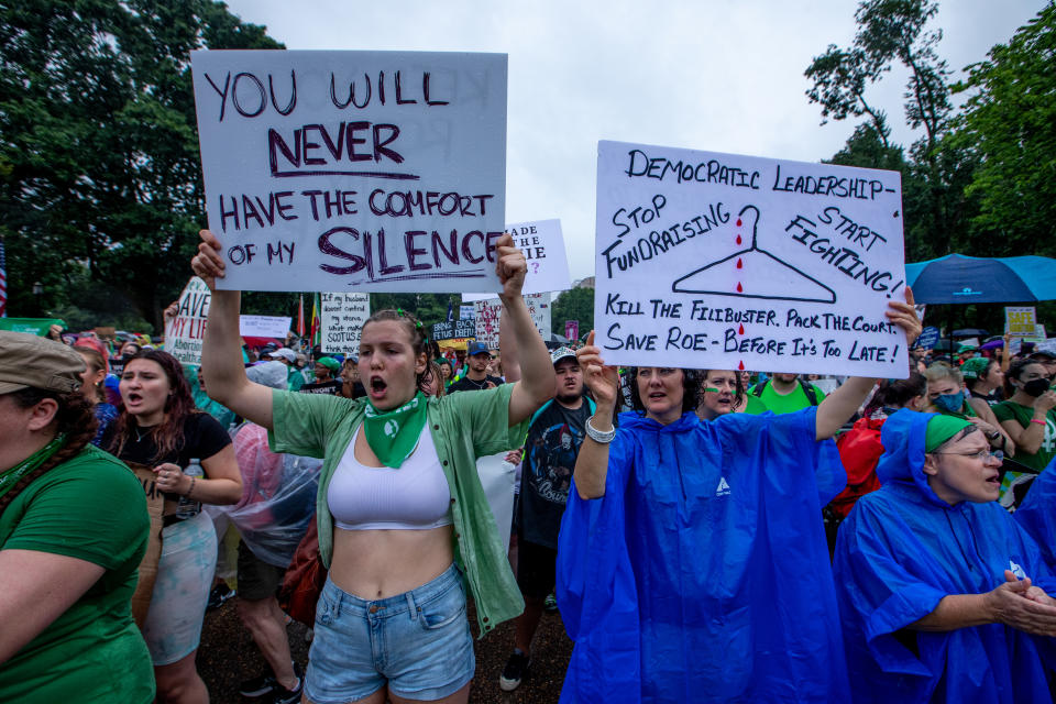 A crowd of abortion rights activists marches. One protester holds a sign reading: You will never have the comfort of my silence.