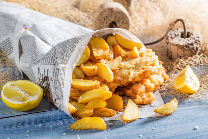 Fish and chips wrapped in newspaper with lemon wedges