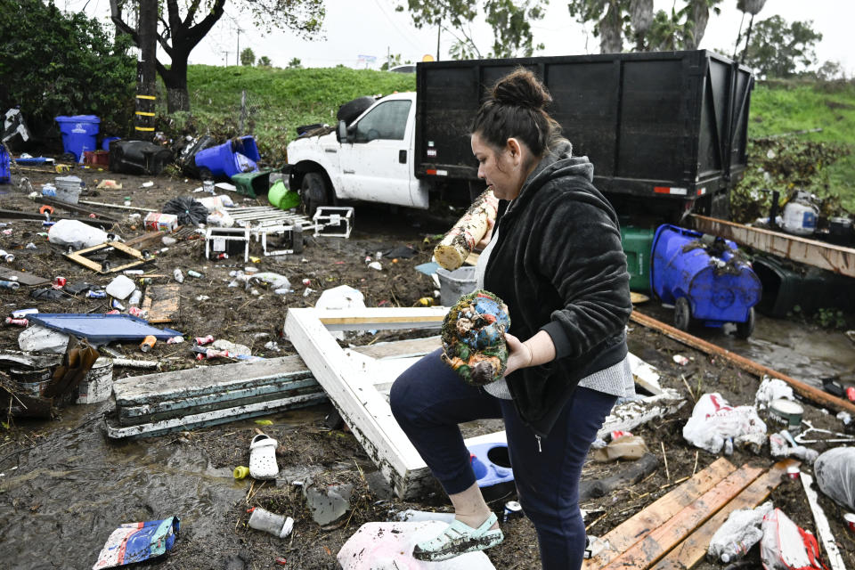 Marlene Sanchez-Barriento salavages items behind her home damaged by flooding, Tuesday, Jan. 23, 2024, in. Sanchez-Barriento's home was damaged when flood waters rushed though her home on Monday, Jan. 23. (AP Photo/Denis Poroy)