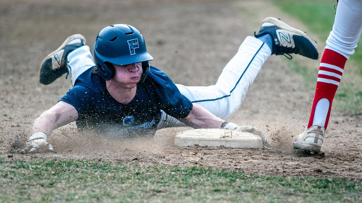 Franklin High School's Ben Yuknis slides safely into third base during a baseball scrimmage against Holliston, March 27, 2024.