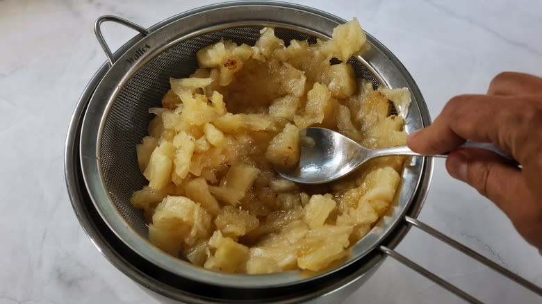 pressing sieve of pineapple with spoon