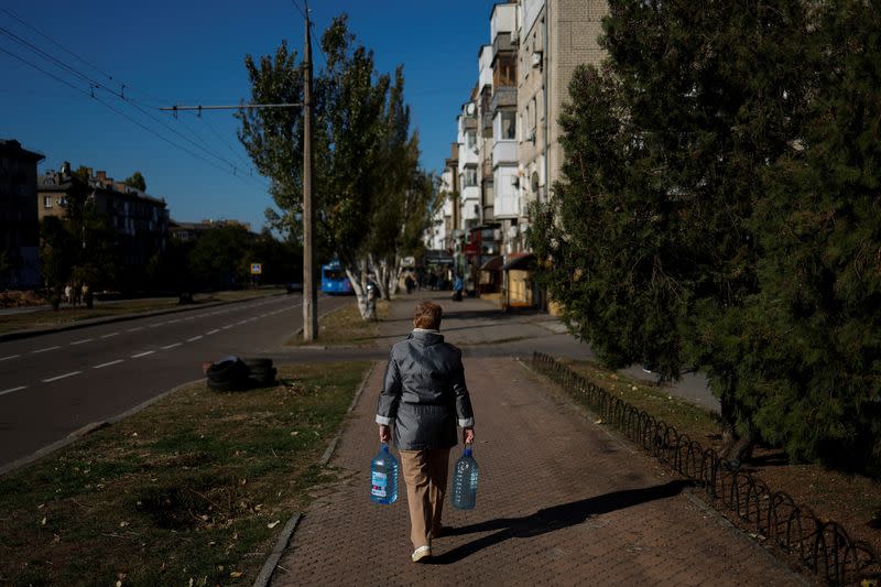 Local woman carries bottles of fresh drinking water in Mykolaiv