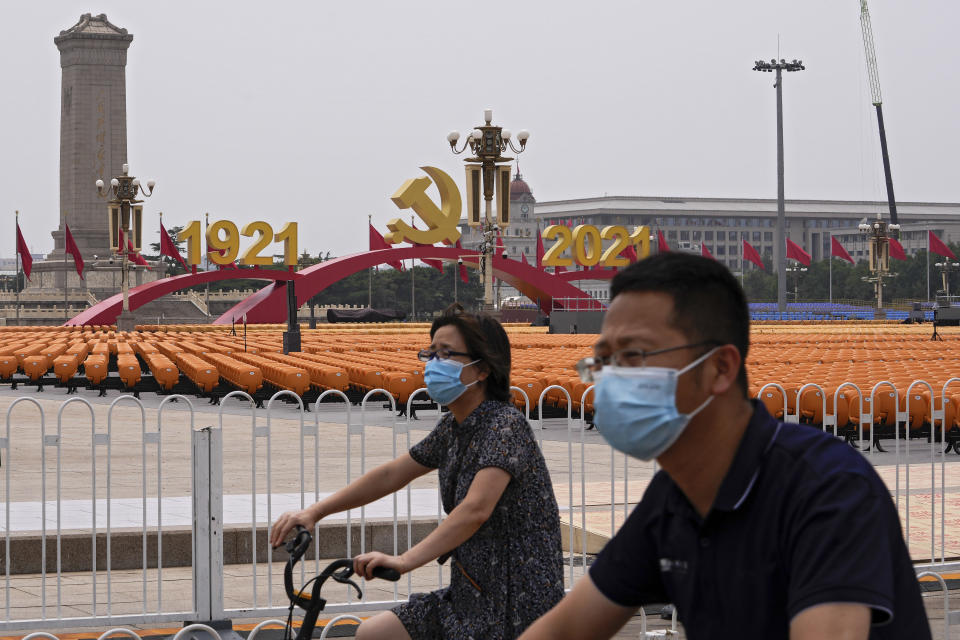 People ride bicycle past Tiananmen Square displaying a platform with a Communist Party's logo and hundreds of seats in Beijing, Monday, June 28, 2021. China is marking the centenary of its ruling Communist Party this week by heralding what it says is its growing influence abroad, along with success in battling corruption at home. (AP Photo/Andy Wong)