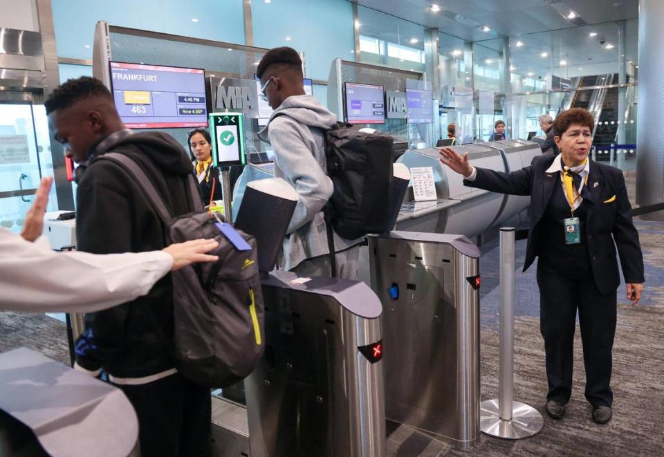 Eva Burgos, passenger service agent, right, of Swissport, assist passengers before boarding Lufthansa flight 463 from Miami International Airport to Frankfurt on August 9, 2023, to get their pictures taken using the new facial-recognition technology at Gate J17. Carl Juste/cjuste@miamiherald.com