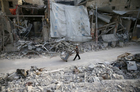 A man pushes a cart past damaged buildings at the besieged town of Douma, Eastern Ghouta, Damascus, Syria March 5, 2018. REUTERS/Bassam Khabieh
