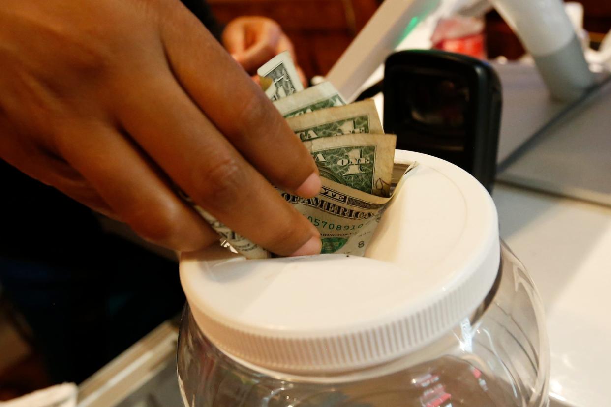 A staff member stuff tips in the tip jar at the Munch Hut in downtown Athens, Ga., on Wednesday, April 28, 2021.