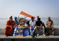 A cricket fan dressed as a Hindu holy man, or Sadhu, sits next to portraits of Indian cricketer Sachin Tendulkar outside a stadium in Mumbai November 16, 2013. Tendulkar did not get a chance to bat again in his final test but India's 'Little Master' was allowed to bowl a couple of overs on Saturday before drawing his 24-year glittering career to an emotional conclusion. REUTERS/Danish Siddiqui