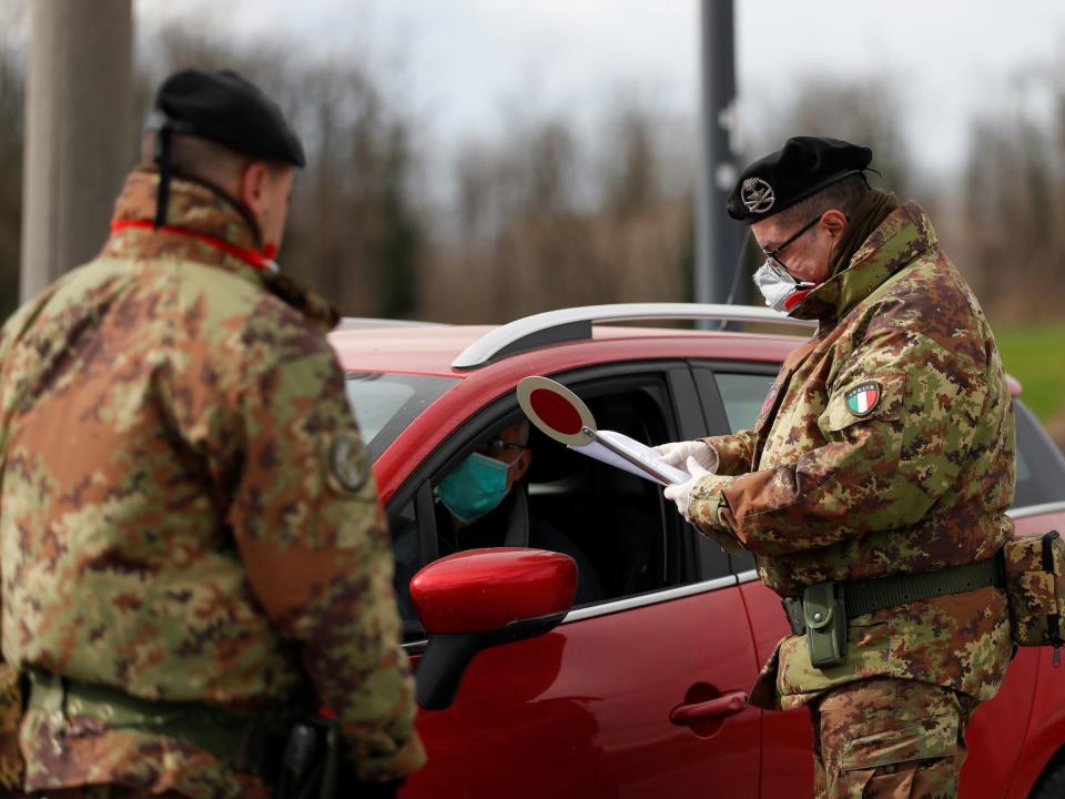 Members of the Italian army wearing protective face masks check the permission of a driver to enter the red zone of Turano Lodigiano, closed off due to a coronavirus outbreak in northern Italy, in Turano Lodigiano, Italy, February 26, 2020.