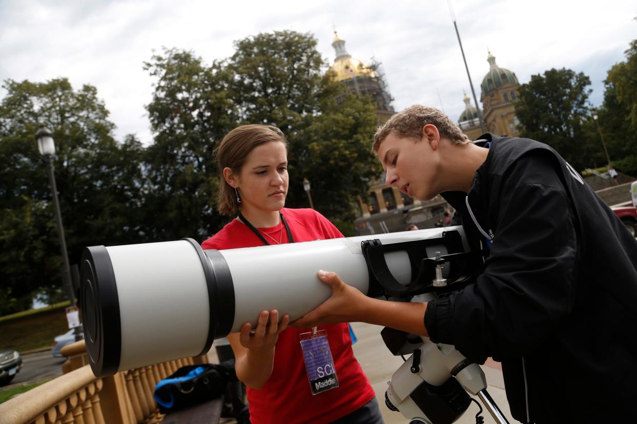 Maddie Beeler (left) with the Iowa Science Center holds the telescope as volunteer Coby Konkol, 16, puts it in place Monday, Aug. 21, 2017, as they get ready for the solar eclipse watch party outside the Iowa State Capitol in Des Moines.
