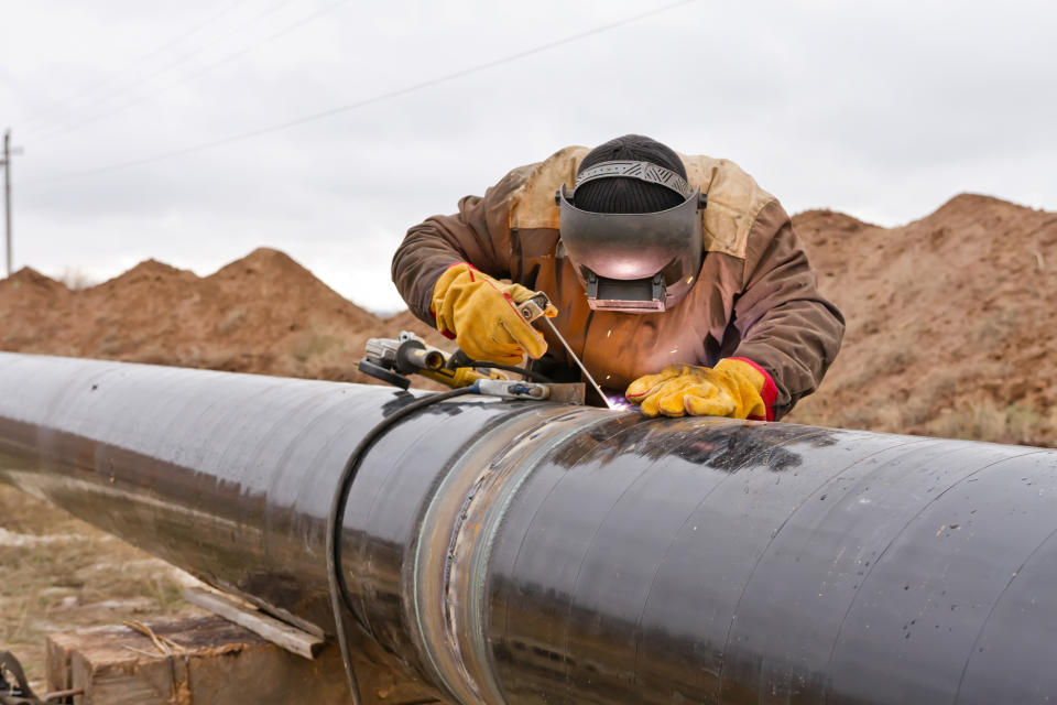 A person welding an oil pipeline