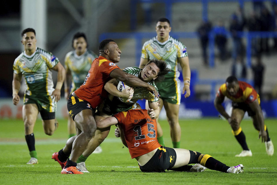 Cook Islands' Rua Ngatikaura is tackled by Papua New Guinea's MacKenzie Yei, left, and Dan Russell during the Rugby League World Cup group D match between Papua New Guinea and Cook Islands at The Halliwell Jones Stadium, Warrington, England, Tuesday Oct. 25, 2022. (Mike Egerton/PA via AP)