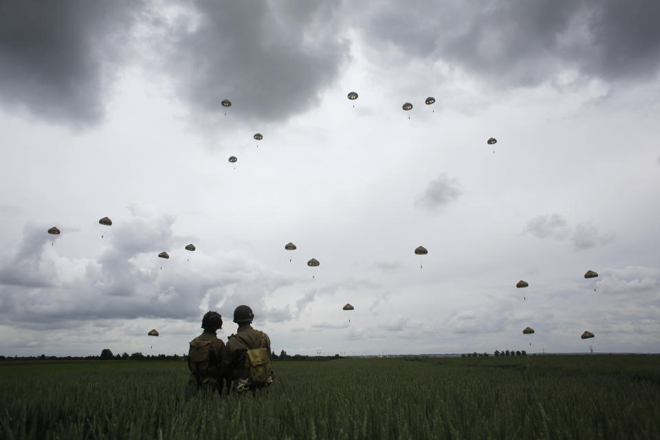 WWII enthusiasts watch French and British parachutists jumping during a commemorative parachute jump over Sannerville, Normandy, Wednesday, June 5, 2019. Extensive commemorations are being held in the U.K. and France to honor the nearly 160,000 troops from Britain, the United States, Canada and other nations who landed in Normandy on June 6, 1944 in history's biggest amphibious invasion. (AP Photo/Thibault Camus)