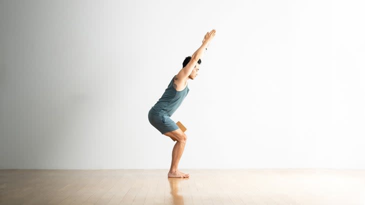 Hiro Landazuri practices chair pose with a cork block between his thighs