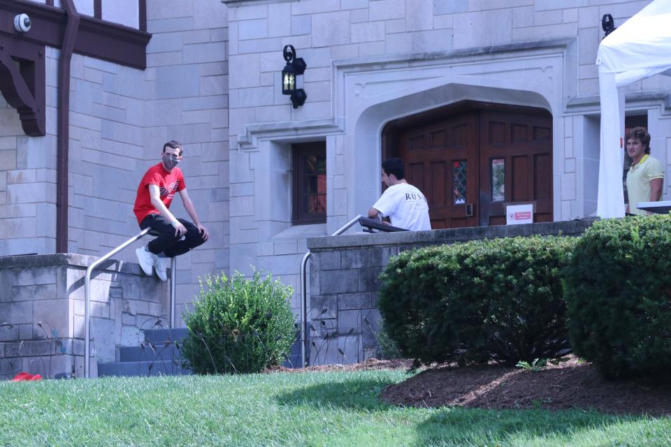People sit outside the Phi Kappa Tau fraternity house on the Indiana University campus.