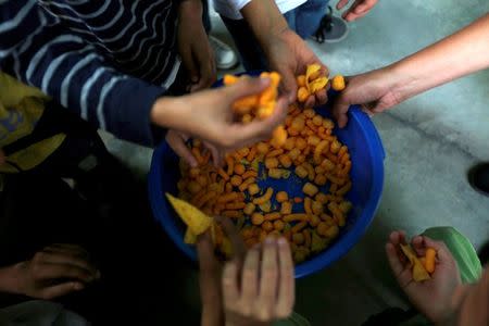 Students grab snacks during an activity for the end of the school year at the Padre Jose Maria Velaz school in Caracas, Venezuela July 12, 2016. REUTERS/Carlos Jasso