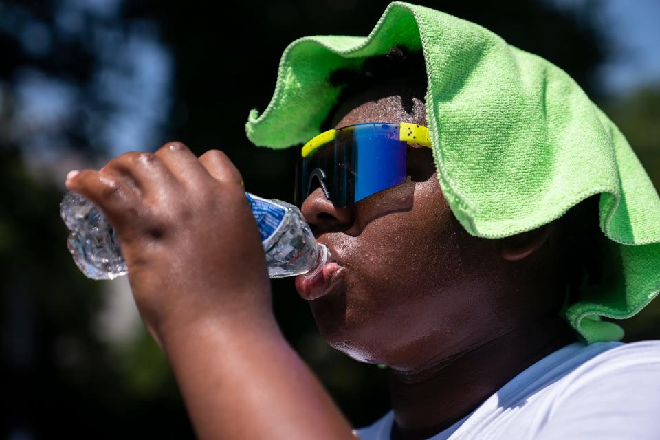 Amir Brown, 15, tries to cool down while helping his mother set up a stand selling cold drinks near the National Mall in Washington, D.C.
