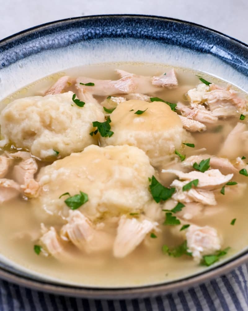 chicken and dumpling soup in a blue rimmed bowl