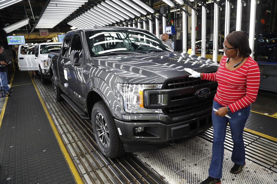 FILE- In this Sept. 27, 2018, file photo United Auto Workers' assemblyman Kelly Coman gives a final look to an assembled 2018 Ford F-150 truck on the assembly line at the Ford Rouge assembly plant in Dearborn, Mich. On Friday, Dec. 14, the Federal Reserve reports on U.S. industrial production for November. (AP Photo/Carlos Osorio, File)