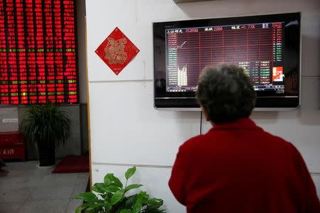 An investor looks at an electronic board showing stock information on the first trading day after the New Year holiday at a brokerage house in Shanghai, China, January 3, 2017. REUTERS/Aly Song