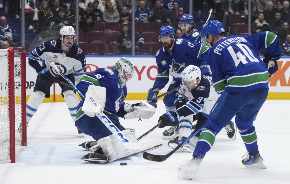 Vancouver Canucks goalie Thatcher Demko stops Winnipeg Jets' Cole Perfetti (91) as Vancouver's Elias Pettersson (40) and Filip Hronek (17) and Winnipeg's Sean Monahan, back left, watch during the second period of an NHL hockey game Saturday, Feb. 17, 2024, in Vancouver, British Columbia. (Darryl Dyck/The Canadian Press via AP)