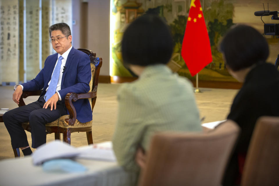 Staff members watch as Chinese Vice Minister of Foreign Affairs Le Yucheng speaks during an interview with the Associated Press at the Ministry of Foreign Affairs in Beijing, Friday, April 16, 2021. Le spoke to AP on a wide range of issues during an interview on Friday including climate change and US-China relations. (AP Photo/Mark Schiefelbein)