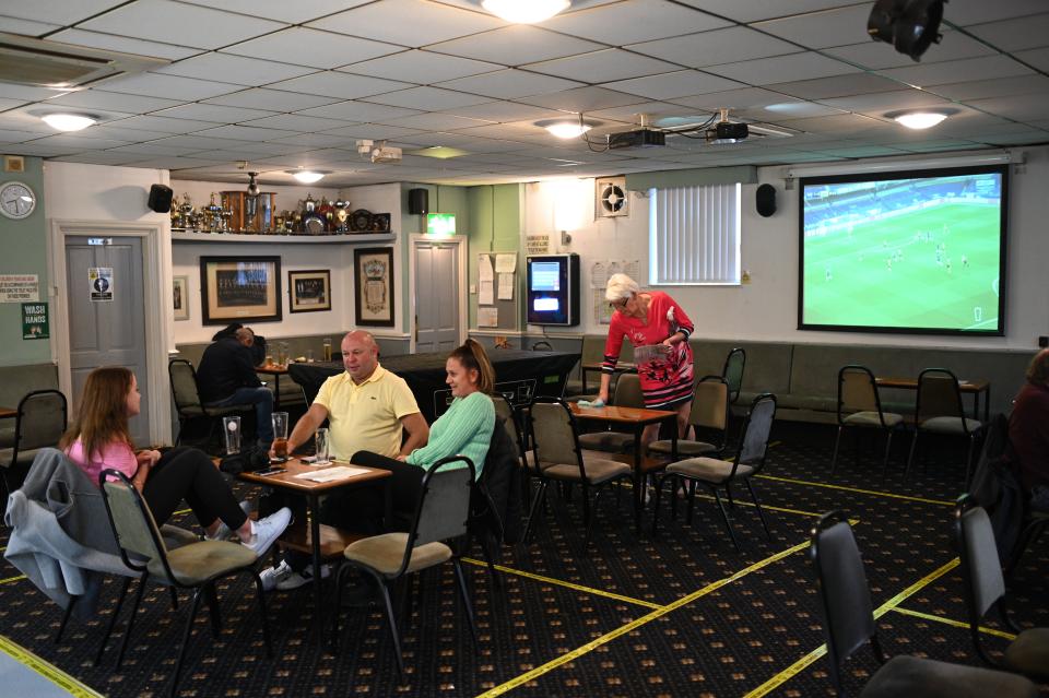 Members and guests enjoy a drink with yellow tape on the carpet aiding social distancing inside the Ridge Hill Working Men's Club in Stalybridge, northwest England, on July 4, 2020, as restrictions are further eased during the novel coronavirus COVID-19 pandemic. - Pubs in England reopen on Saturday for the first time since late March, bringing cheer to drinkers and the industry but fears of public disorder and fresh coronavirus cases. (Photo by Oli SCARFF / AFP) (Photo by OLI SCARFF/AFP via Getty Images)