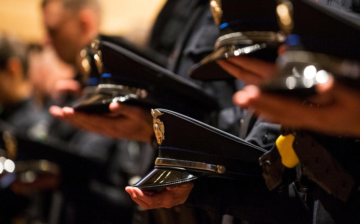 Members of the Austin Police Department hold their hats during a graduation ceremony in 2017.