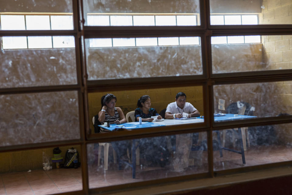 Electoral workers wait for people to cast their votes in Chinautla, on the outskirts of Guatemala City, Sunday, Aug. 11, 2019. Guatemalans go the polls Sunday in the second-round presidential runoff, pitting ex-first lady Sandra Torres against conservative Alejandro Giammattei in a nation beset by poverty, unemployment and emigration. (AP Photo/Oliver de Ros)