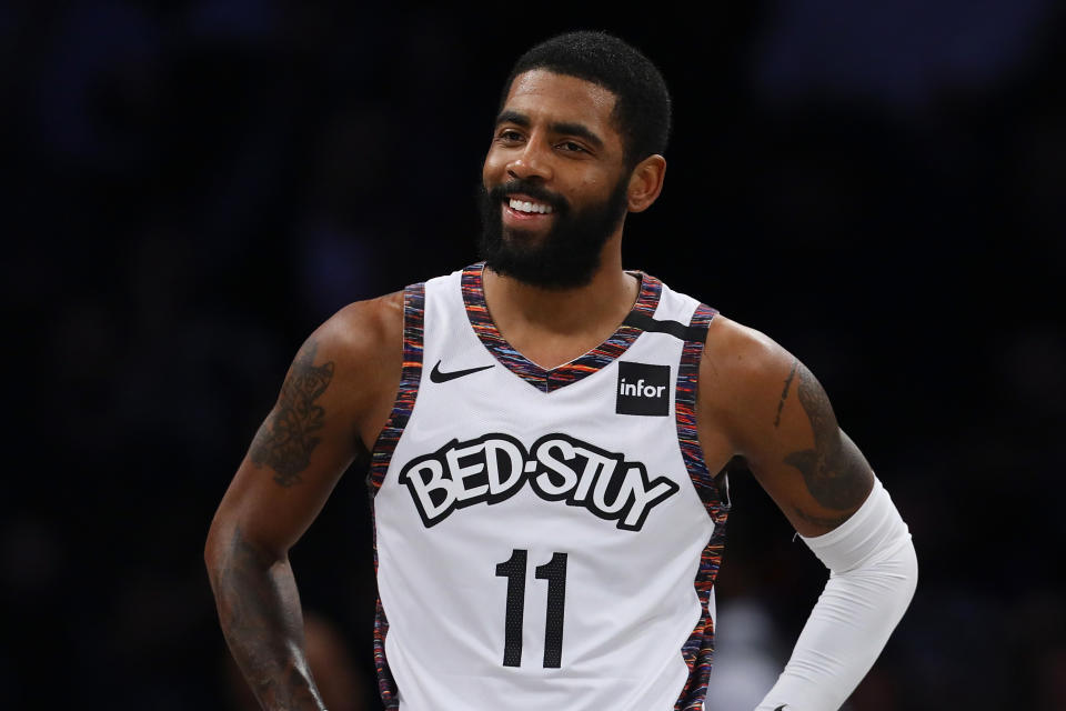 Kyrie Irving with a slight smile and his hands on his hips during a game.