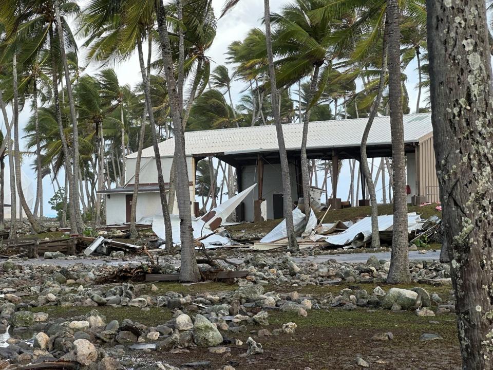 The Roi-Namur church steeple rests on the coral-strewn grounds on the opposite side of the Tradewinds Theater, background, from where it once stood. The steeple is the only part of the church recognizable.